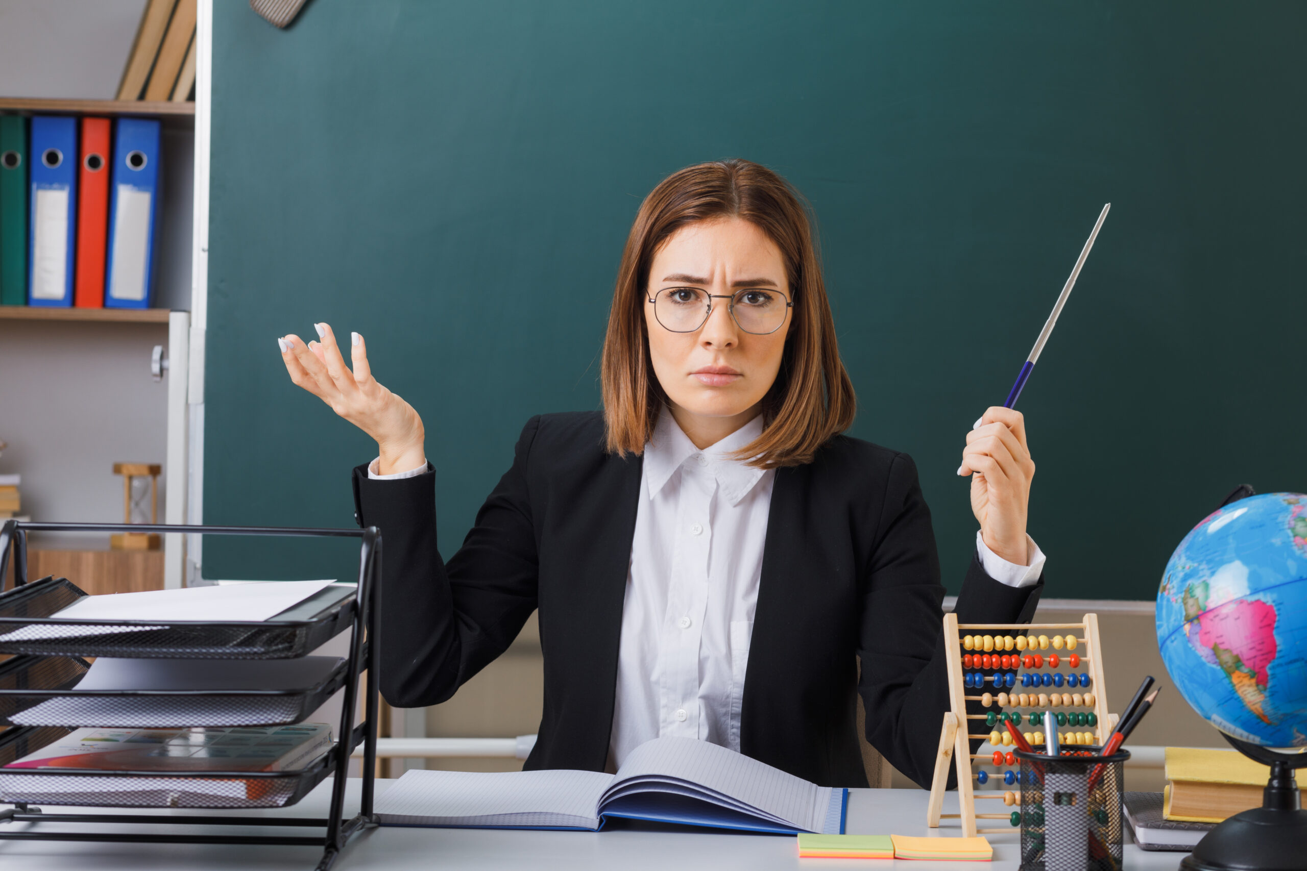 young woman teacher wearing glasses sitting at school desk in front of blackboard in classroom and globe checking class register holding pointer looking displeased raising arm in displeasure SSUCv3H4sIAAAAAAAACpyRz27DIAzG75P2DhHnRiJ/mjZ7lWoHB0iCSqEC0mmq+u4zECrOyyn+2f7szzw/P6qKTOAkI1/VM0QYS6U25y14aTRieti5FZoLW5KH7QZaAsGlN1aCKuEEnq0abgKh3pQK+BWTxHnwmxMuTN8RAy8W1EjwLZFWvKS4yomYxA5MEXIomNumyDJK4v/qTD/f2Q0sQrPfuHBhxAolIBm5pFJy/fHC3kprsHFpClcPw0CFgq5QulvJpF6KNuPXePbcxsymvQ0rvDcnypg7TCqceEZNkfkKzmE5z7wYxPCRza2Yo42PBnZVwvElQth07Ti09Nzjdz7Sph/2gvR6q0SduE4WwphdJS+ty7ABmflwahinNWtHUfetoDWwmdbTkVI2j3TsTxMe/vUHAAD//wMAv1aat5gCAAA=